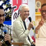 Three men in a panel: left in a patterned shirt holding a microphone, center with white hair in a light jacket smiling into a mic, right in a beige shirt and glasses making a thoughtful gesture.