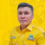 Portrait of a man in a bright yellow uniform with patches, standing against a solid yellow backdrop.