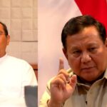 Two men at a panel, each with a raised index finger; left in a white shirt, right in a beige uniform, with a red‑white backdrop behind them.
