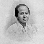 Black-and-white studio portrait of a woman with a neat bun, wearing a light blouse.