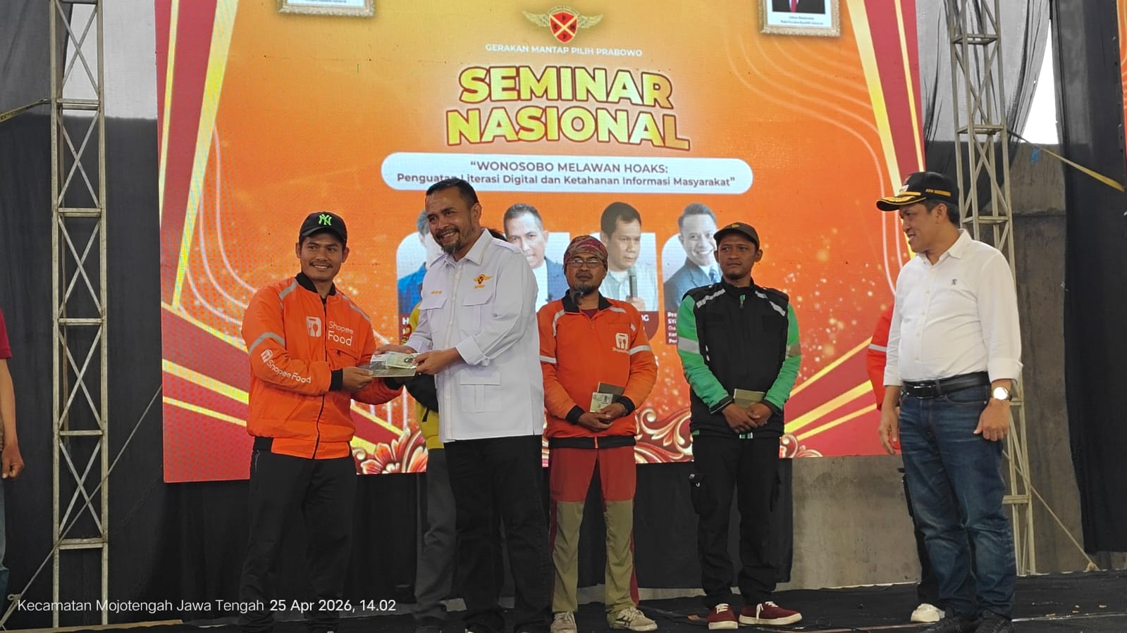 Man in a white shirt hands an award envelope to a delivery rider in an orange Shopee Food uniform on a stage during a national seminar.