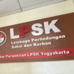 Maroon wall sign for LPSK (Lembaga Perlindungan Saksi dan Korban) with circular logo on left and large white LPSK letters across the top.