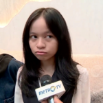 Young woman seated on a beige sofa during a Metro TV interview, holding a microphone close to her face.