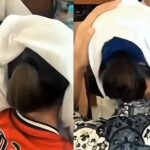 Two people seated, white cloths draped over their heads as they bend forward; one in red and the other in a blue patterned top.