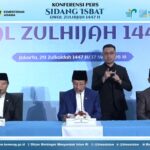 Four men sit at a conference table during a Kemenag press briefing for Sidang Isbat 1447 H, with a blue backdrop and Indonesian banners behind them.