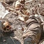 Person lying in rubble with a gloved hand reaching toward a skull among the debris