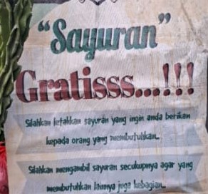 Poster reading 'Sayuran Gratis!!!' inviting people to take free vegetables for those in need and to take only what they need so others can have some.